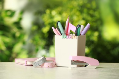 Stapler, holder and other different stationery on white table