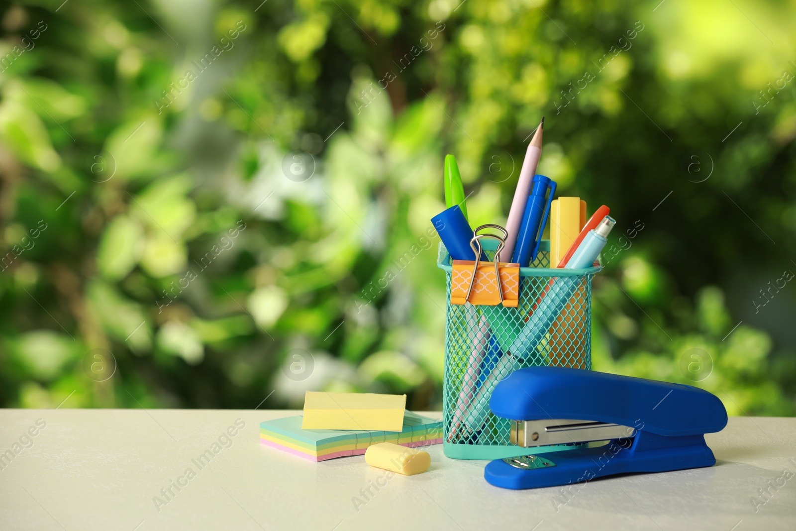 Photo of Stapler, holder and other different stationery on white table, space for text