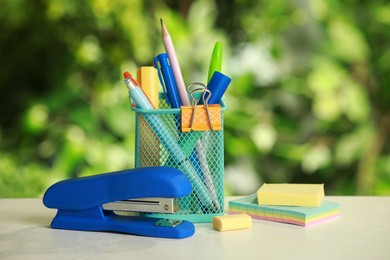 Stapler, holder and other different stationery on white table