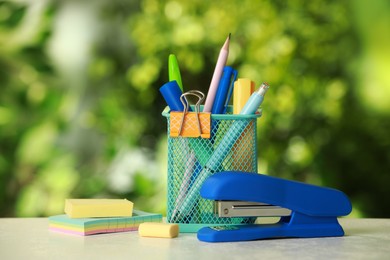 Photo of Stapler, holder and other different stationery on white table