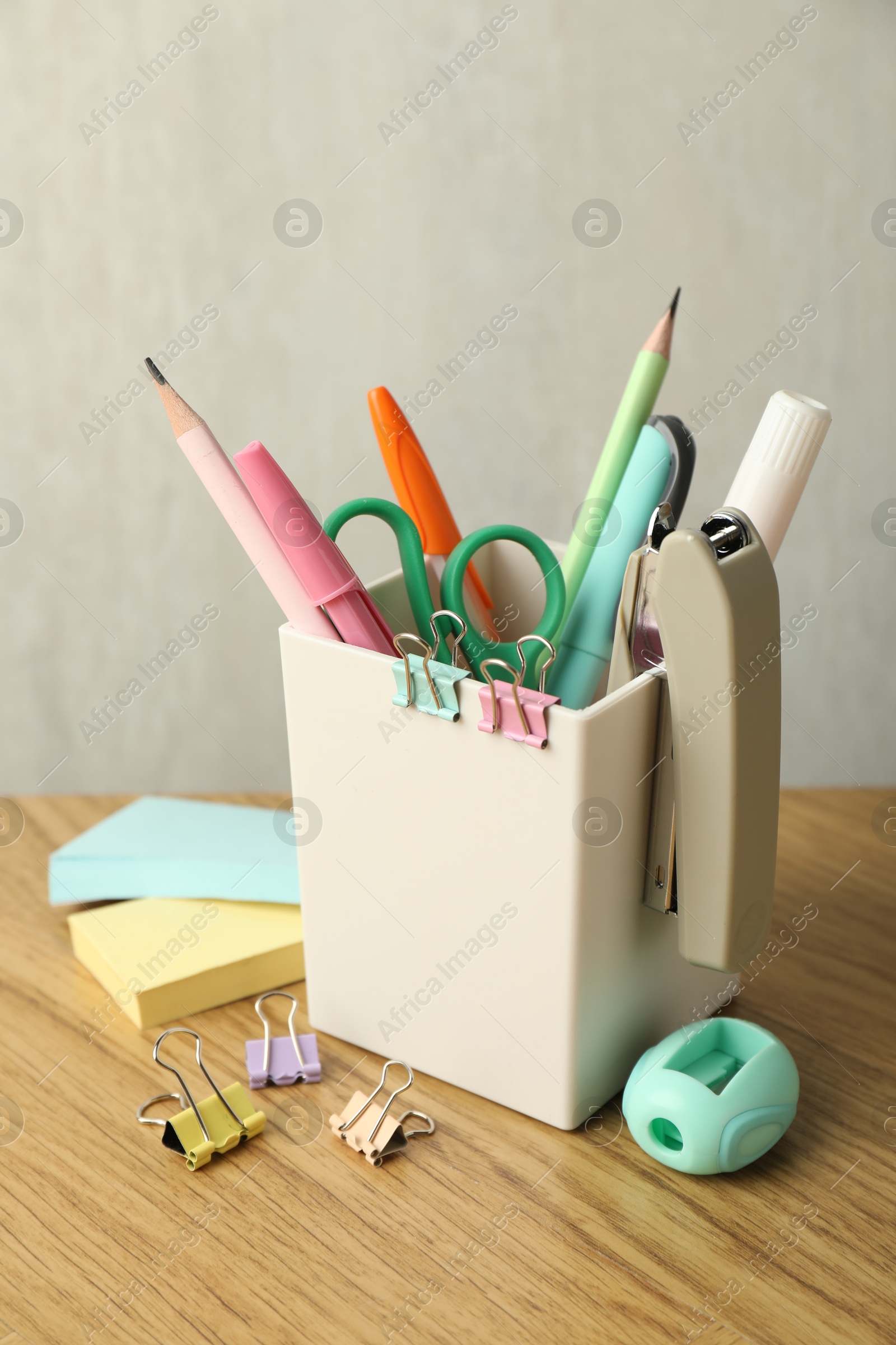 Photo of Stapler, holder and other different stationery on wooden table