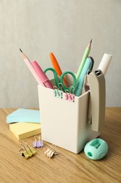 Photo of Stapler, holder and other different stationery on wooden table