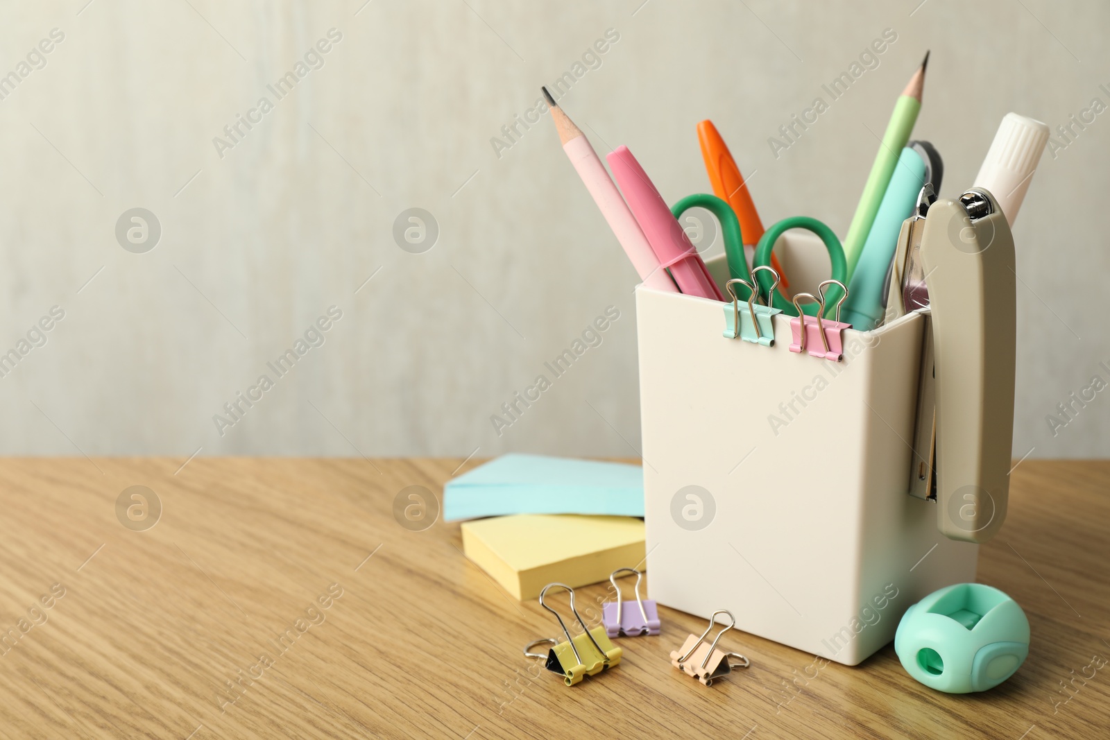 Photo of Stapler, holder and other different stationery on wooden table, space for text