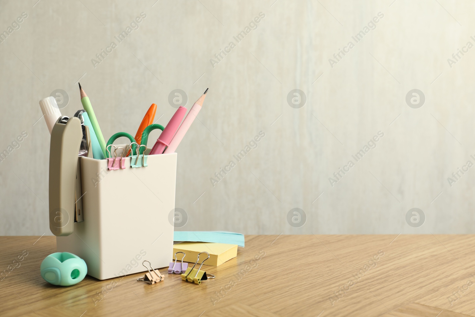 Photo of Stapler, holder and other different stationery on wooden table, space for text