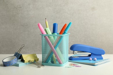 Stapler, holder and other different stationery on white table