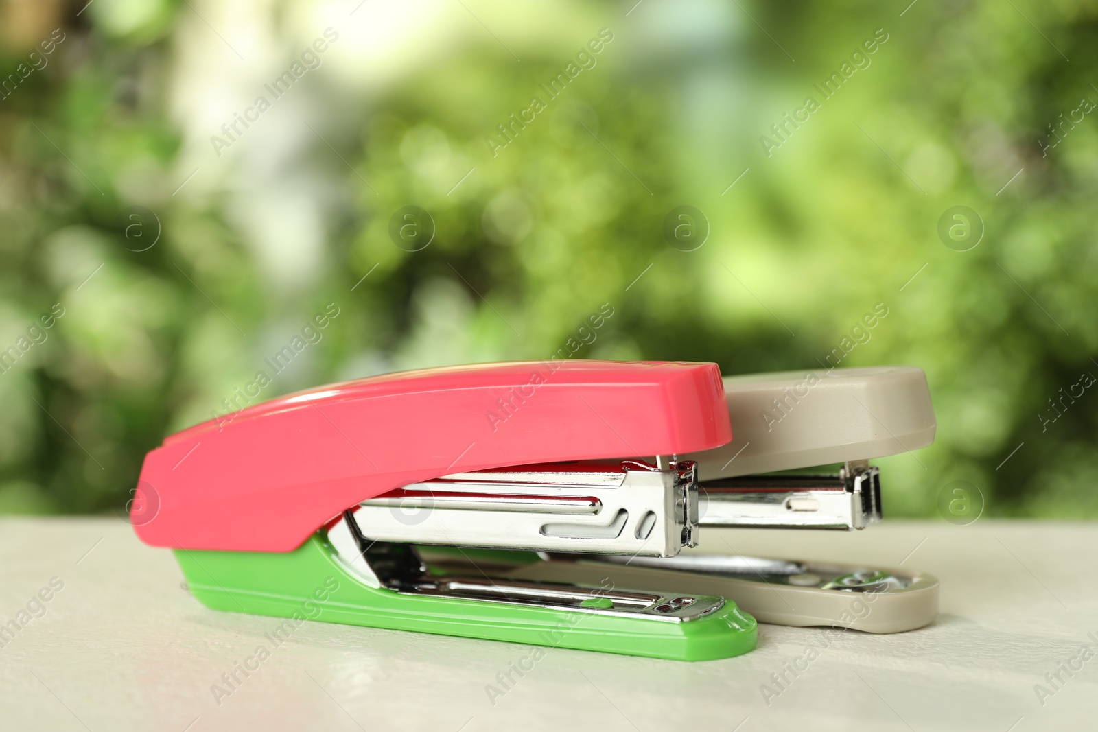 Photo of Two staplers on white table against blurred background