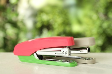 Photo of Two staplers on white table against blurred background