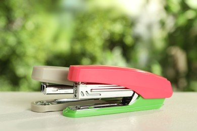 Photo of Two staplers on white table against blurred background