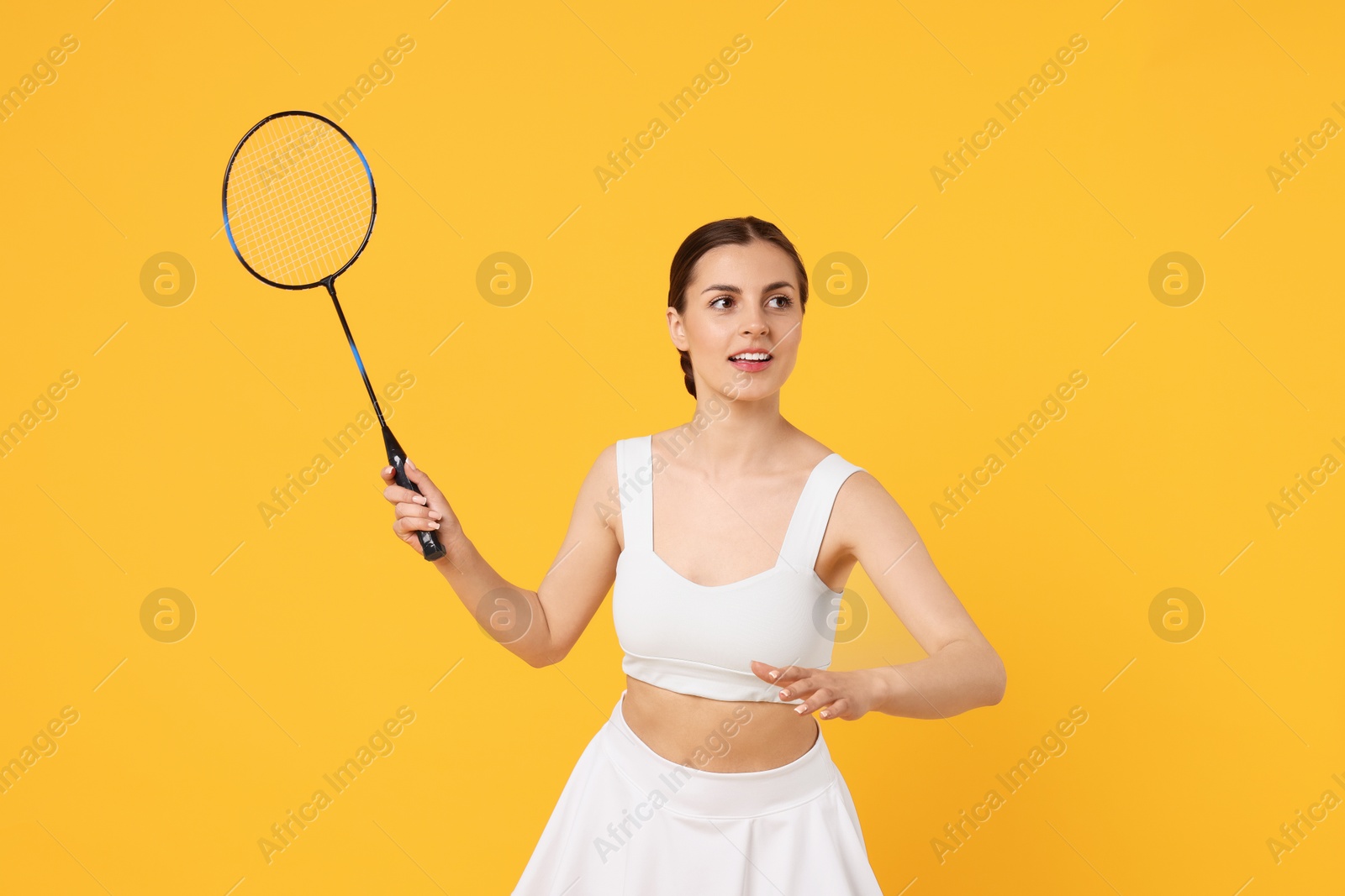 Photo of Young woman with badminton racket on orange background
