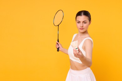 Young woman with badminton racket and shuttlecock on orange background, space for text