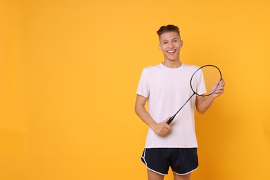 Photo of Young man with badminton racket on orange background