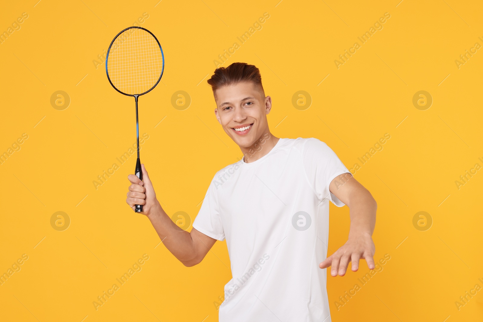 Photo of Young man with badminton racket on orange background