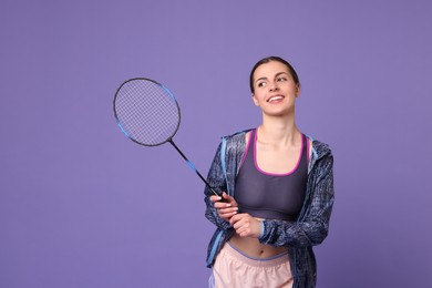 Young woman with badminton racket on purple background