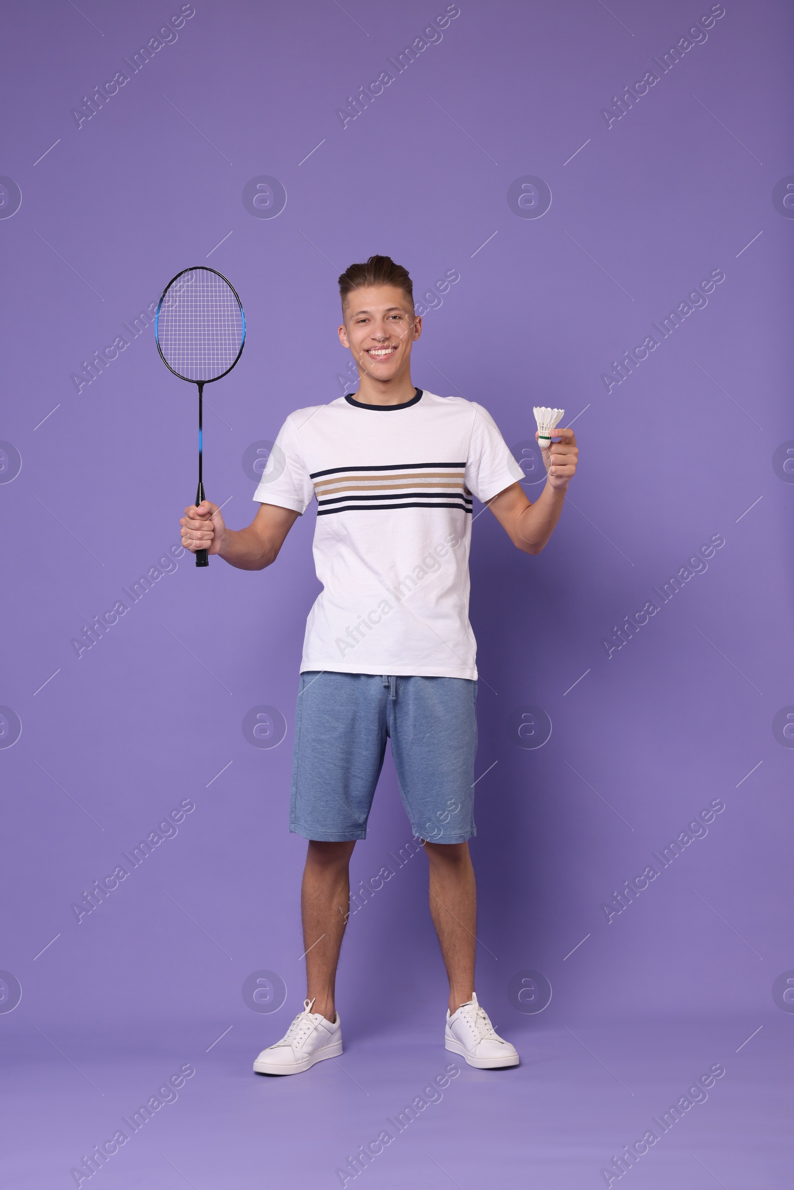 Photo of Young man with badminton racket and shuttlecock on purple background