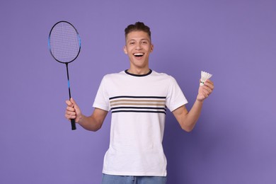 Young man with badminton racket and shuttlecock on purple background