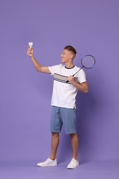 Photo of Young man with badminton racket and shuttlecock on purple background