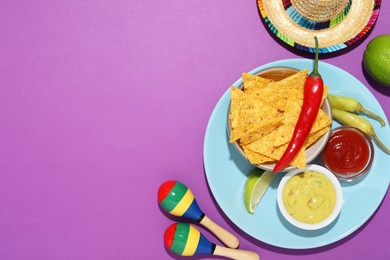 Photo of Nachos chips, guacamole, chili pepper, maracas and Mexican sombrero hat on purple background, flat lay. Space for text