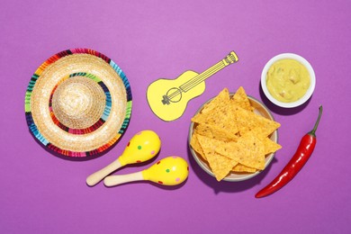Mexican sombrero hat, nachos chips, guacamole, maracas, chili pepper and paper guitar on purple background, flat lay