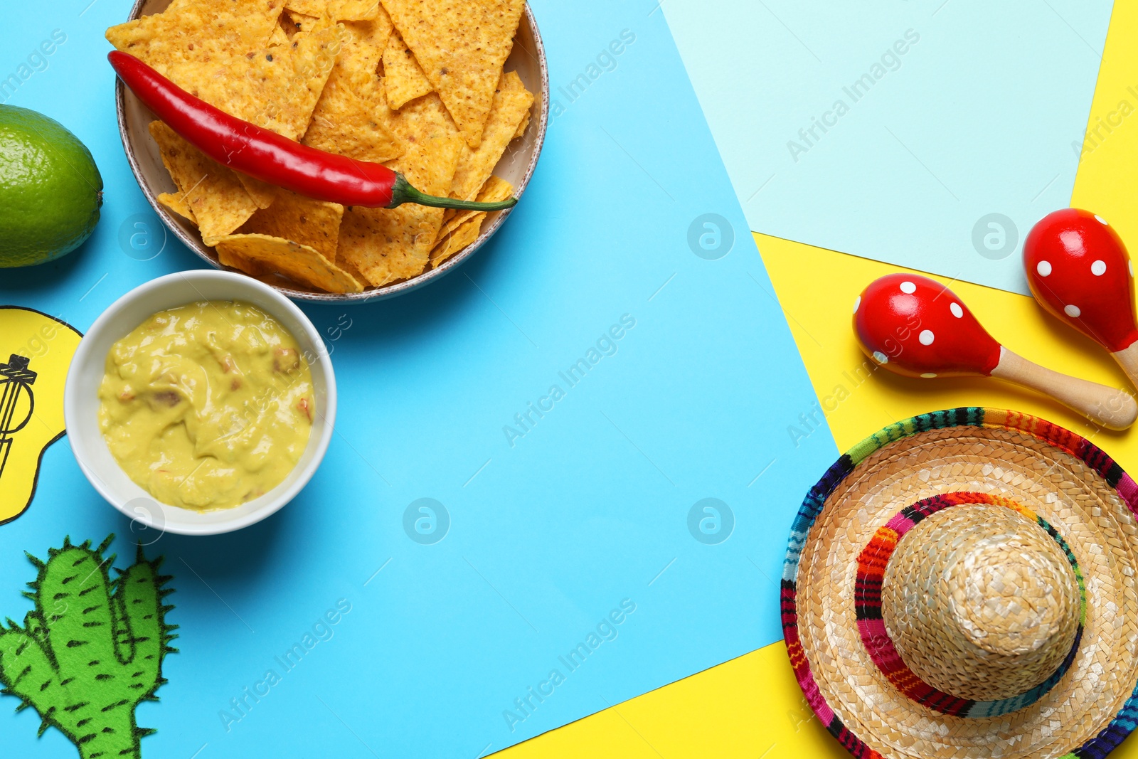 Photo of Mexican sombrero hat, maracas, guacamole, nachos chips, chili and paper cactus on color background, flat lay. Space for text