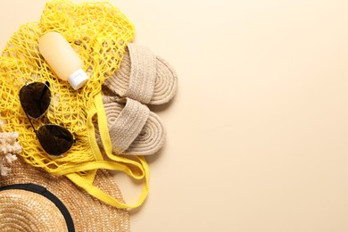 Photo of String bag and different beach accessories on beige background, top view. Space for text