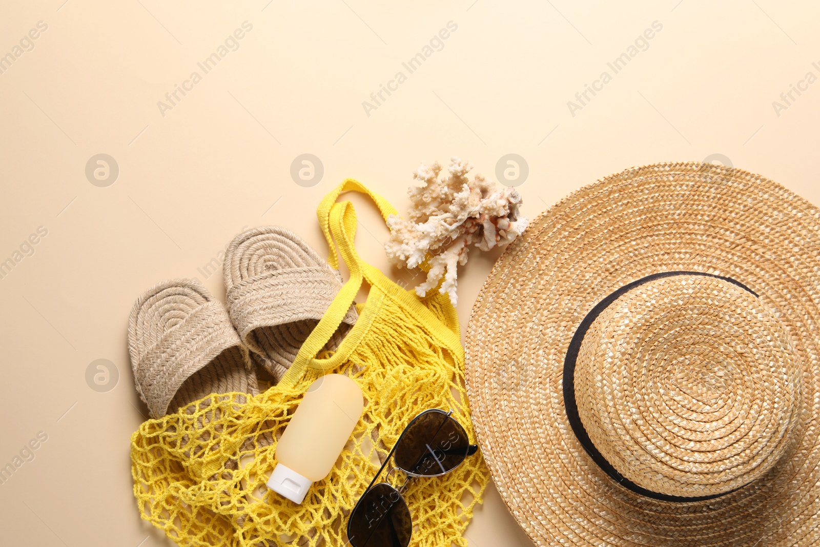 Photo of String bag and different beach accessories on beige background, top view. Space for text