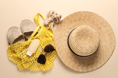 String bag and different beach accessories on beige background, top view