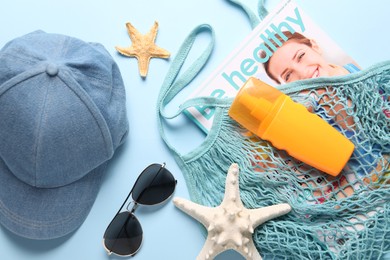 String bag and different beach accessories on light blue background, flat lay