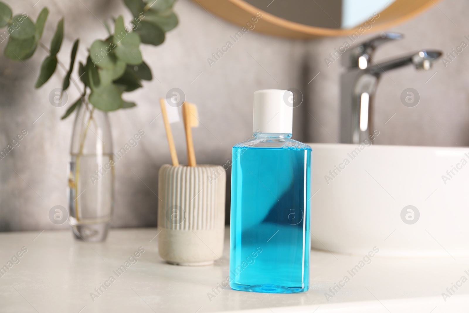 Photo of Bottle of mouthwash and toothbrushes on white countertop in bathroom