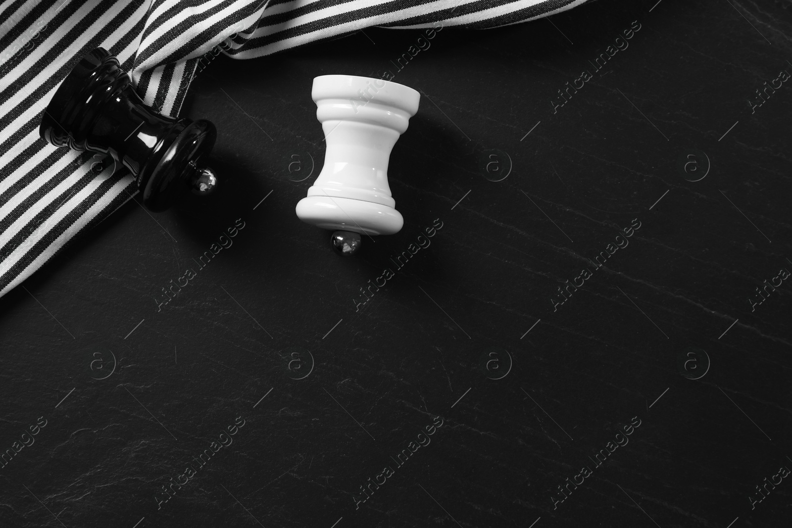 Photo of Salt and pepper shakers on black textured table, flat lay. Space for text