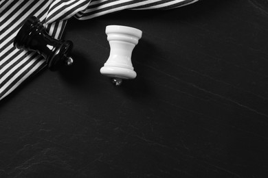 Photo of Salt and pepper shakers on black textured table, flat lay. Space for text