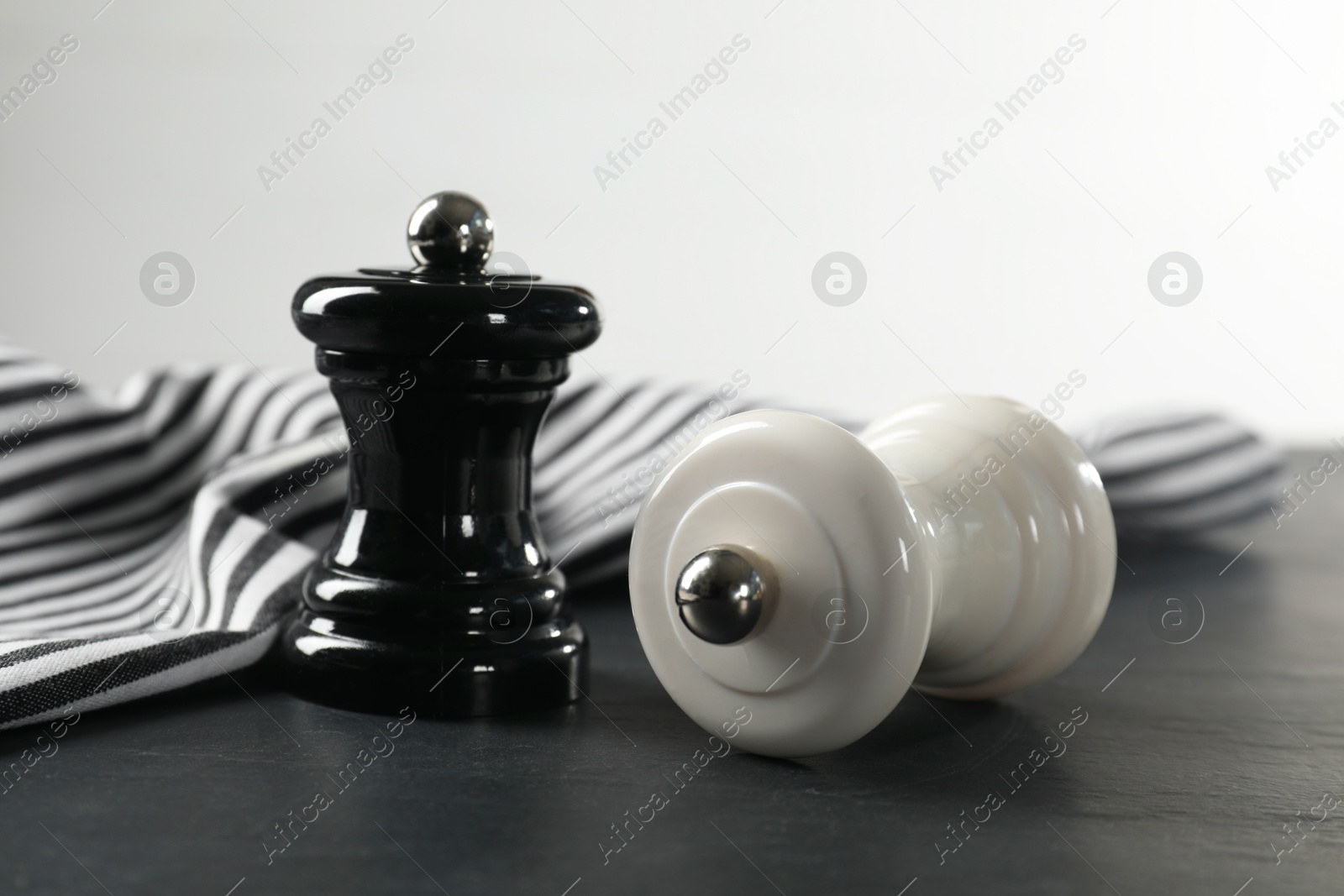 Photo of Salt and pepper shakers on black textured table, closeup