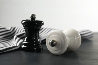 Photo of Salt and pepper shakers on black textured table, closeup