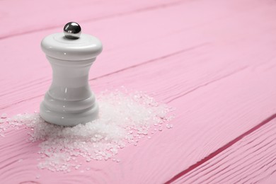 Photo of Salt shaker on pink wooden table, closeup. Space for text