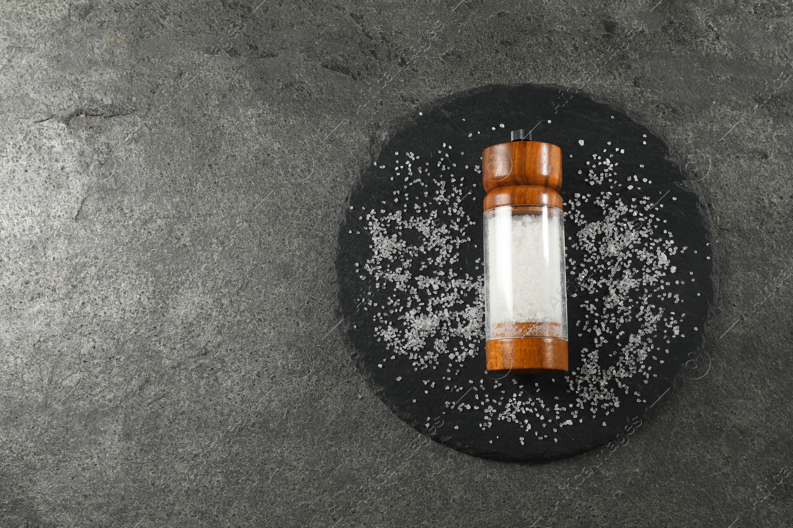 Photo of Salt shaker on grey textured table, top view. Space for text