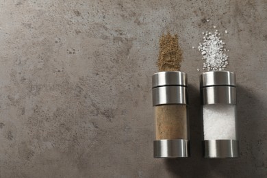 Salt and pepper shakers on grey textured table, flat lay. Space for text