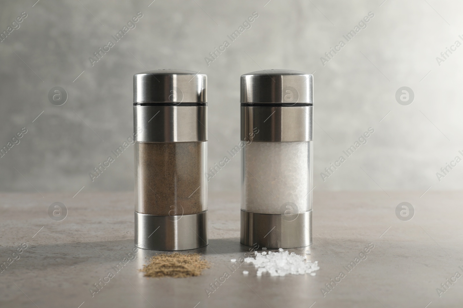 Photo of Salt and pepper shakers on grey textured table, closeup