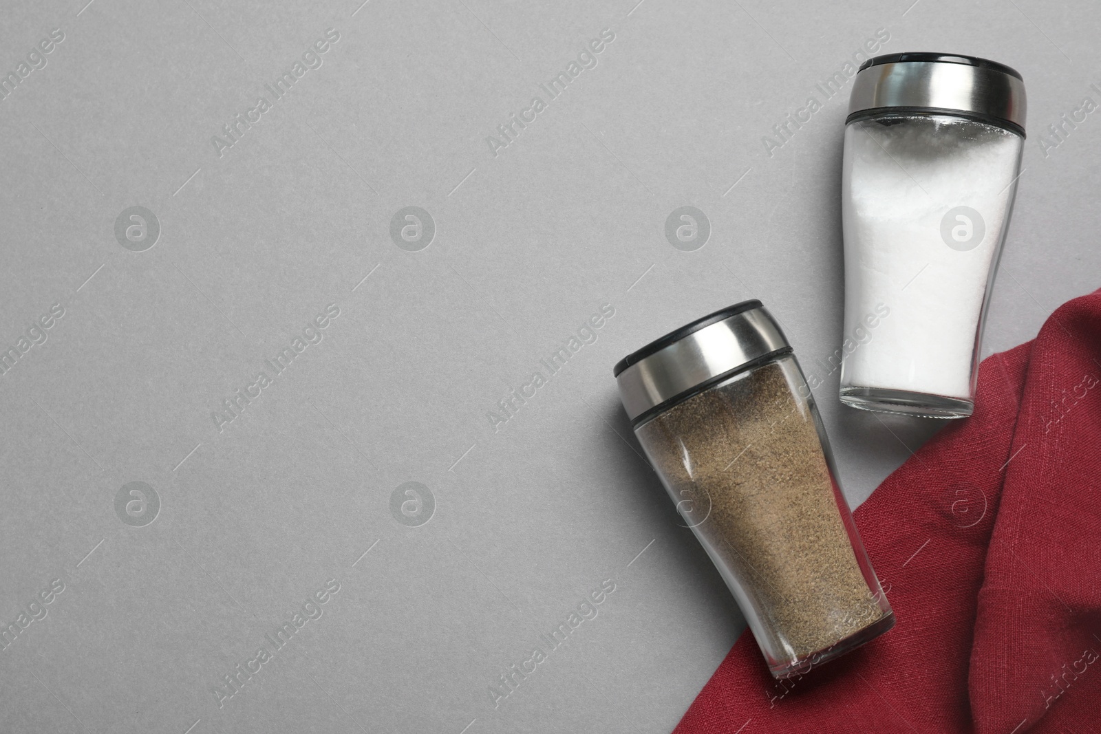 Photo of Salt and pepper shakers on grey table, flat lay. Space for text