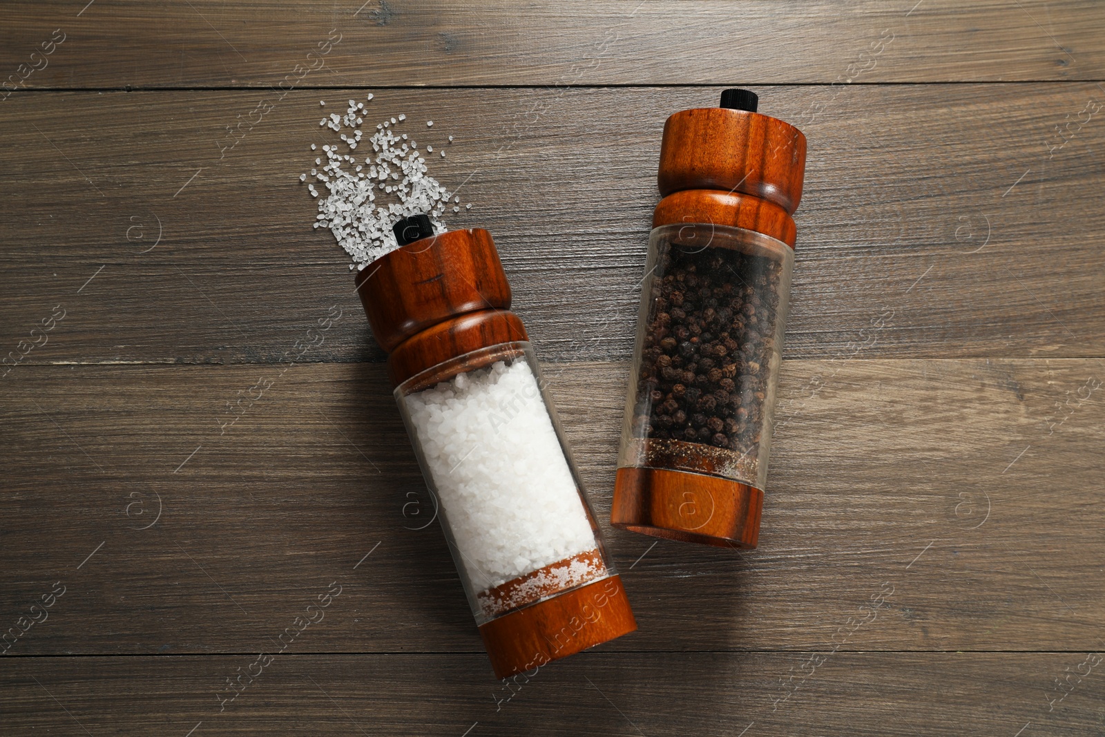 Photo of Salt and pepper shakers on wooden table, flat lay