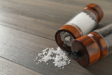 Photo of Salt and pepper shakers on wooden table, closeup. Space for text