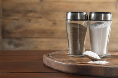 Photo of Salt and pepper shakers on wooden table, closeup. Space for text