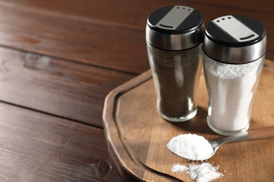 Photo of Salt and pepper shakers on wooden table, closeup. Space for text