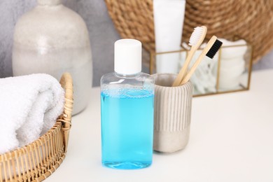 Photo of Bottle of mouthwash and toothbrushes on white table in bathroom