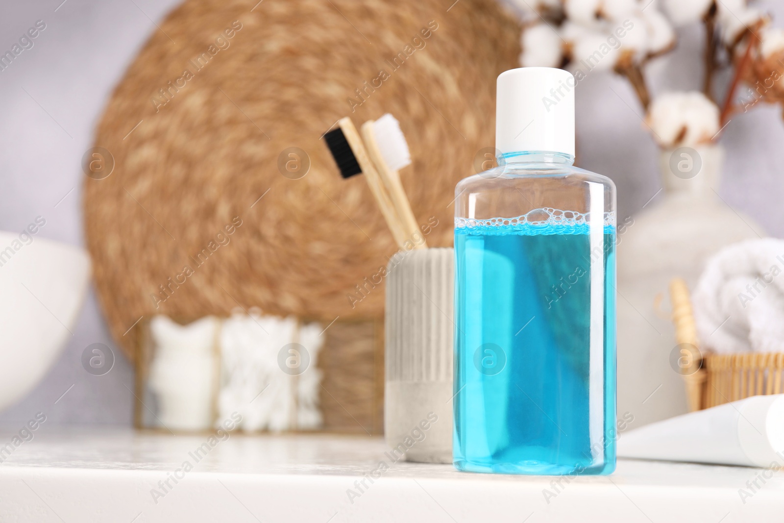 Photo of Bottle of mouthwash and toothbrushes on white table in bathroom, space for text