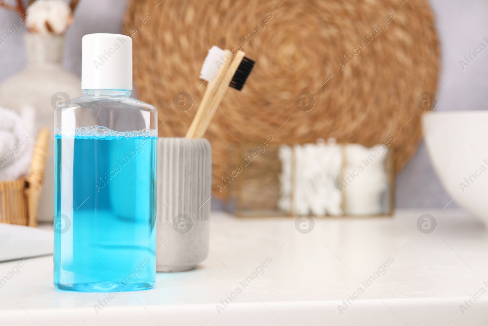 Photo of Bottle of mouthwash and toothbrushes on white table in bathroom, space for text