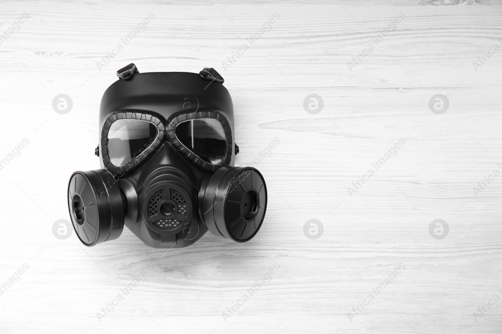 Photo of One gas mask on white wooden background, top view. Space for text