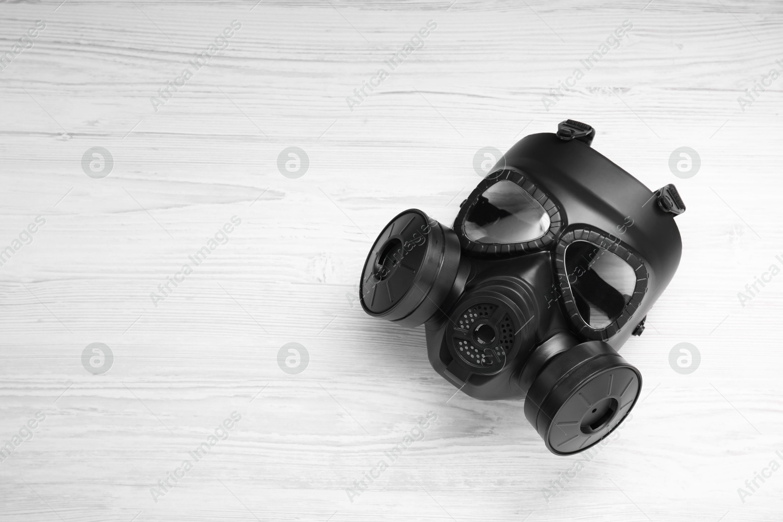 Photo of One gas mask on white wooden background, top view. Space for text