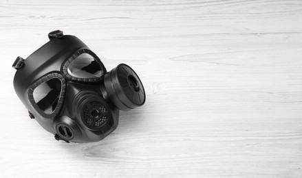 Photo of One gas mask on white wooden background, top view. Space for text