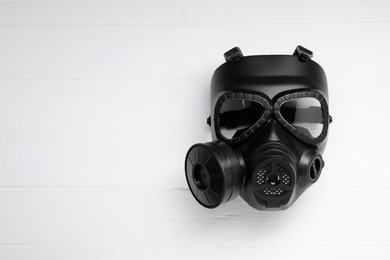 Photo of One gas mask on white wooden background, top view. Space for text