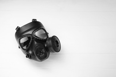 One gas mask on white wooden background, top view. Space for text