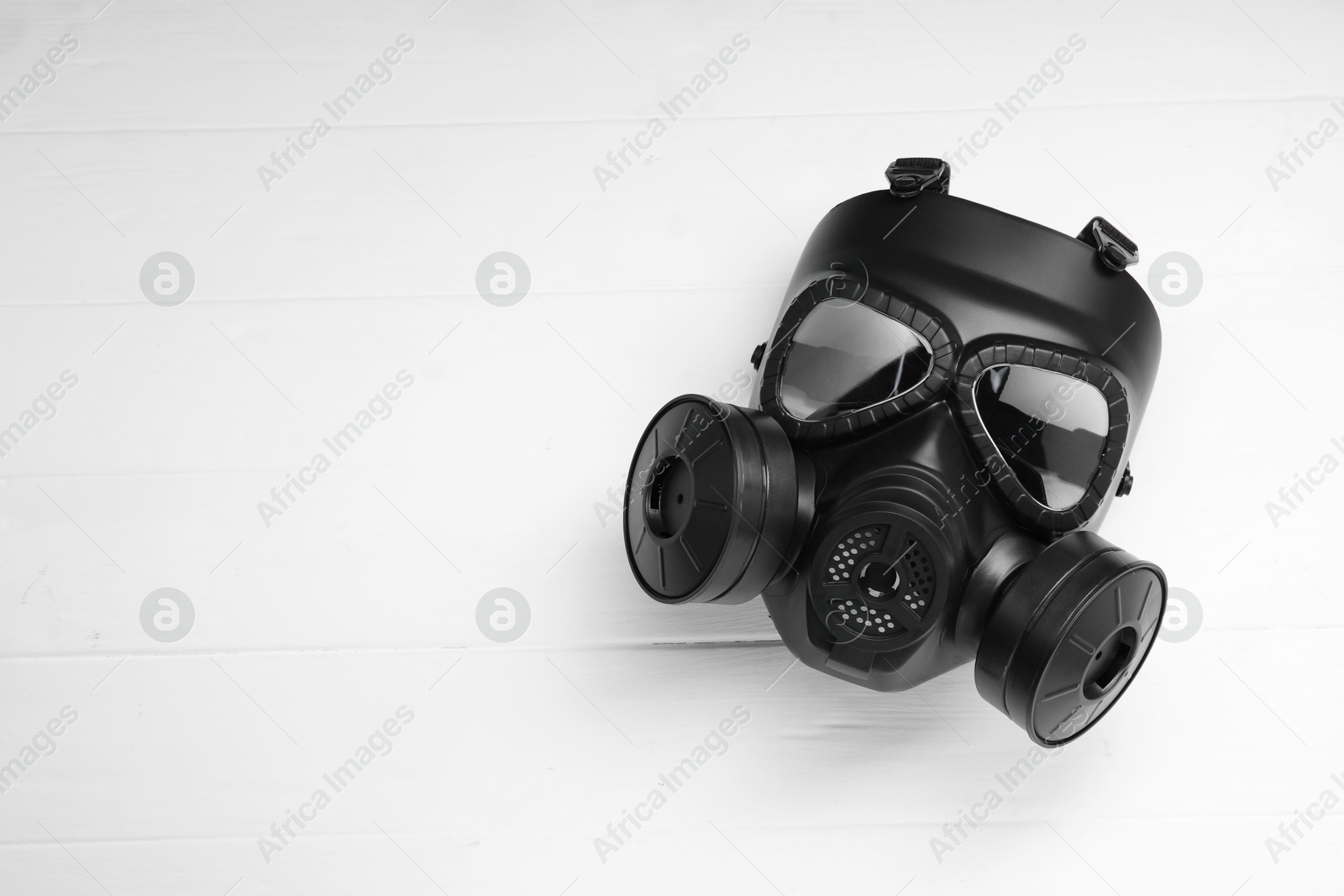 Photo of One gas mask on white wooden background, top view. Space for text